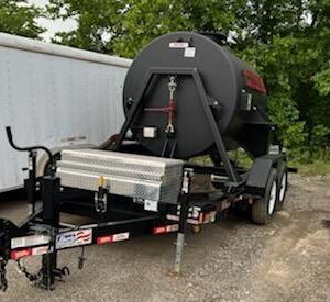 Trailer with mounted cylindrical tank parked outside.