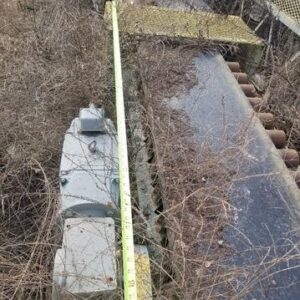 Overgrown machine with measuring tape on top.