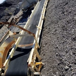 Conveyor belt on rocky terrain under sky.