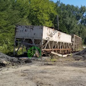 Rusty industrial container in a wooded area.