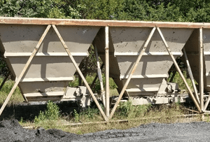 Railway freight cars on tracks, green background.