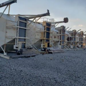 Industrial machinery lying on gravel surface outdoors.