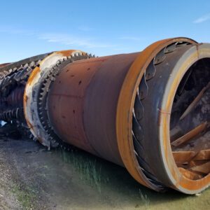 Rusty industrial pipe lying on grassy ground.