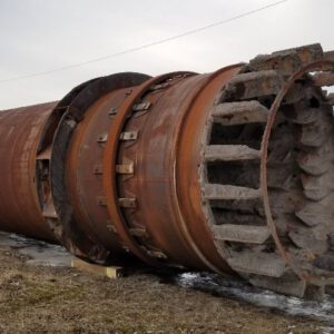 Rusty industrial pipe laying on ground.