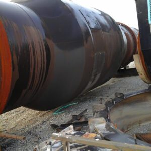 Large rusty metal pipe on gravel ground.