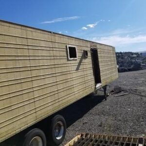 Yellow trailer in a gravel lot.