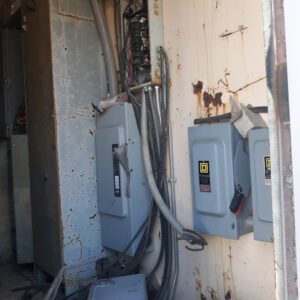 Rusty electrical panels and exposed wiring indoors.