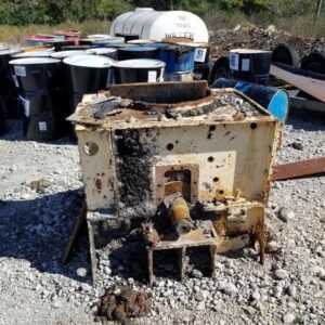 Rusty industrial equipment with metal drums nearby.
