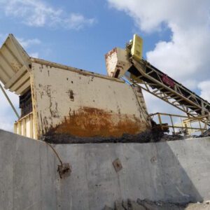 Industrial machinery with conveyor under cloudy sky.