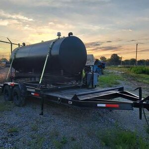 Black tank trailer at sunset in field.
