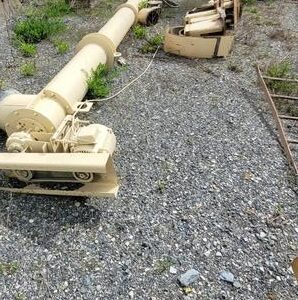 Industrial machinery parts on gravel ground.