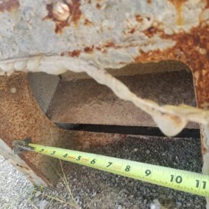 Rusty metal with measuring tape underneath.