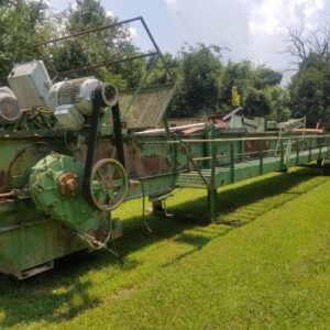 Old green industrial machine on grass field.