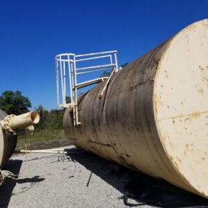 Large metal tanks lying on gravel ground.