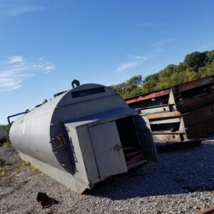 Large metal tank on gravel surface.