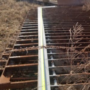 Measuring tape on rusty metal grating outdoors.