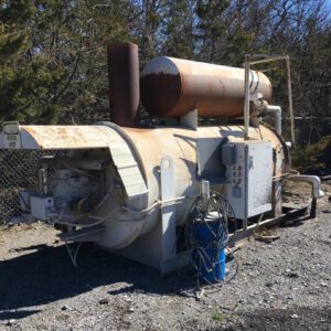 Rusty industrial machine outdoors on gravel surface.