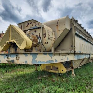 Rusty industrial machine in grassy field.