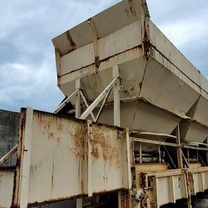 Rusty industrial hopper under cloudy sky.