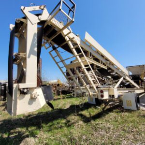 Industrial conveyor equipment on grassy field.
