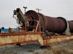 Rusty industrial equipment on a grassy field.