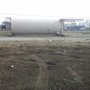 Large industrial tank on grassy field.