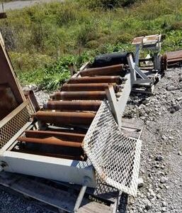 Rusty industrial conveyor belt on gravel ground.