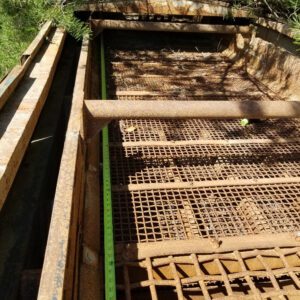 Rusty metal grates with green measuring tape.