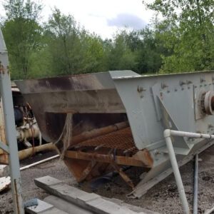 Rusty industrial machinery outdoors near trees.
