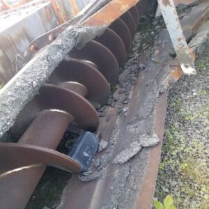 Rusty auger machine with concrete debris.