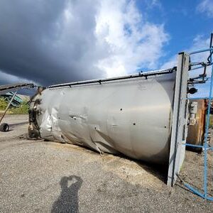 Fallen industrial silo under cloudy sky.