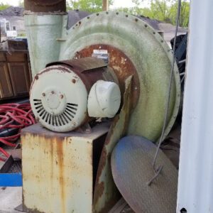 Old industrial fan under wooden shelter.