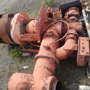 Rusty industrial machinery with pipes on ground.
