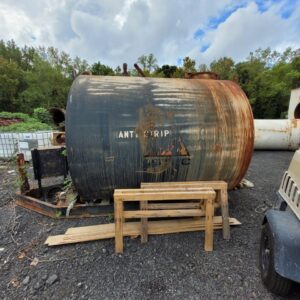Rusty, cylindrical tank in industrial outdoor setting.