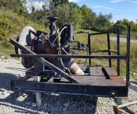Rusty industrial machinery on gravel outdoors.