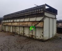 Large, rusty industrial container on concrete ground.