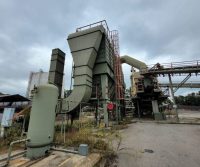 Industrial machinery under cloudy sky at plant.