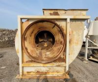Rusty industrial fan on gravel surface.