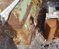 Rusty metal machinery on gravel surface.