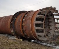 Rusty industrial pipe laying on ground.