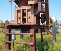 Rusty industrial equipment in overgrown grass field.