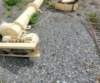 Industrial machinery parts on gravel ground.