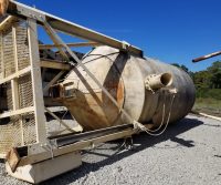 Rusty industrial tank lying on gravel ground.