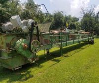Old green industrial machine on grass field.