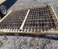 Metal grate lying on gravel ground.
