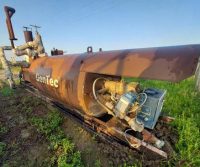 Rusty industrial machinery in outdoor grassy area.