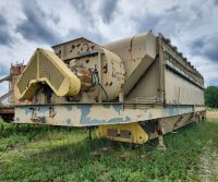 Rusty industrial machine in grassy field.