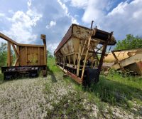 Rusty industrial equipment in overgrown outdoor area.