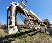 Industrial conveyor equipment on grassy field.