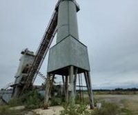 Abandoned industrial tower under cloudy sky.